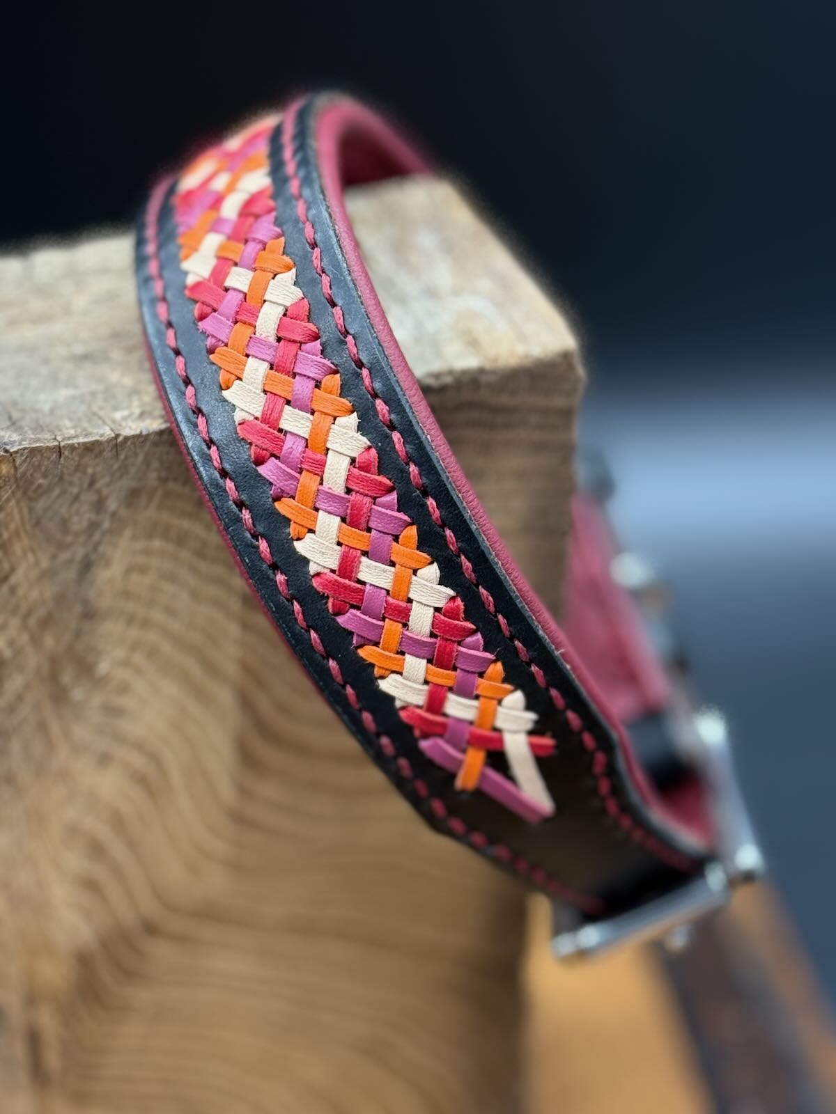 Handgefertigtes Lederhalsband Lace aus schwarzem Geschirrleder mit weinroter Unterfütterung und vierfacher Aufflechtung in Cerise, Rot, Natur und Orange.